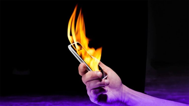 A person holding a smartphone that is on fire.