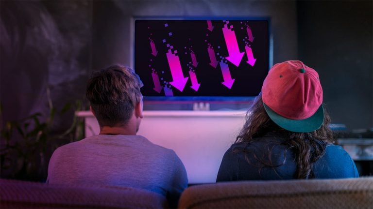 Two people sitting on a couch watching a streaming program on the TV