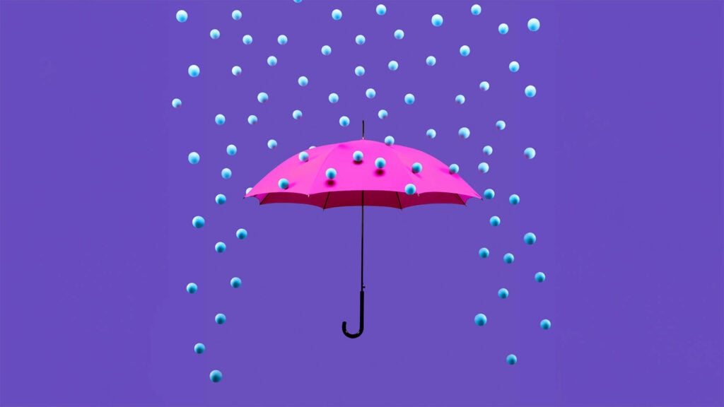 Blue pearl-like balls raining down on an open umbrella.